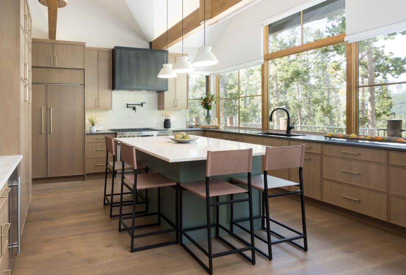 This is a picture of a kitchen featuring rift cut white oak cabinets in the perimeter and a custom green painted island.