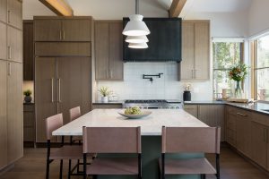 This is a picture of a kitchen featuring rift cut white oak cabinets in the perimeter and a custom green painted island.