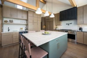 This is a picture of a kitchen featuring rift cut white oak cabinets in the perimeter and a custom green painted island.