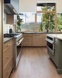 This is a picture of a kitchen featuring rift cut white oak cabinets in the perimeter and a custom green painted island.