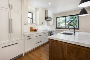 This is a picture of a kitchen featuring Bridgewood cabinetry. The island has Maple cabinetry with Java stain and a painted accessible beige perimeter.