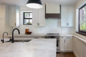 This is a picture of a kitchen featuring Bridgewood cabinetry. The island has Maple cabinetry with Java stain and a painted accessible beige perimeter.