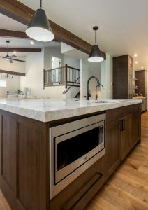 This is a picture of a kitchen featuring Bridgewood cabinetry. The island has Maple cabinetry with Java stain and a painted accessible beige perimeter.