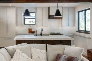 This is a picture of a kitchen featuring Bridgewood cabinetry. The island has Maple cabinetry with Java stain and a painted accessible beige perimeter.