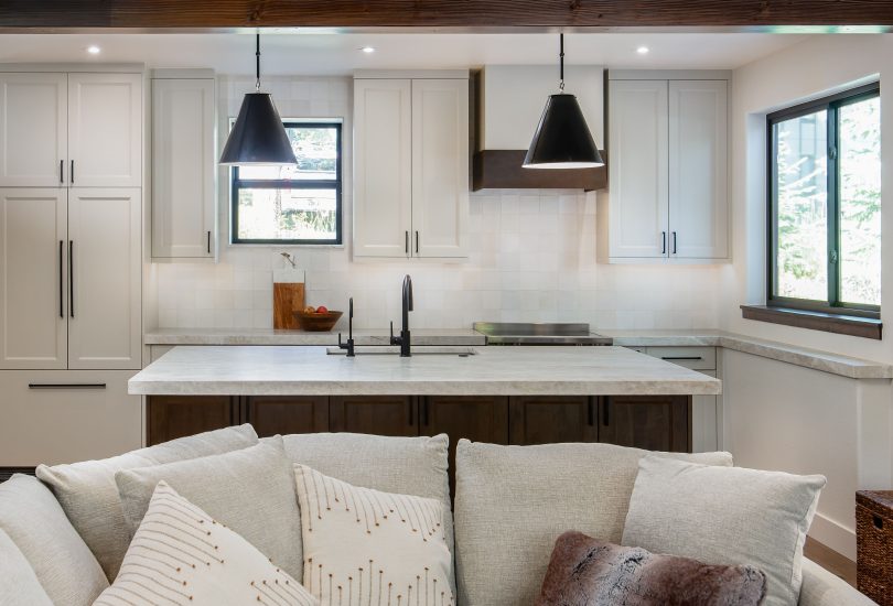 This is a picture of a kitchen featuring Bridgewood cabinetry. The island has Maple cabinetry with Java stain and a painted accessible beige perimeter.